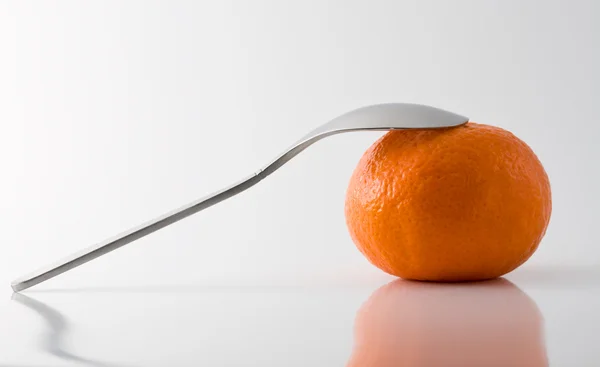 Metal teaspoon leaning on a tangerine — Stock Photo, Image