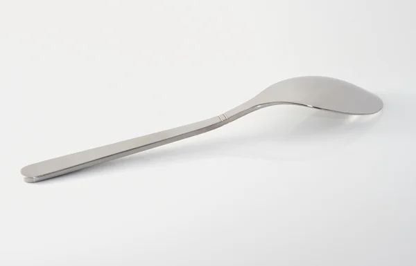 Metal teaspoon on white specular surface — Stock Photo, Image