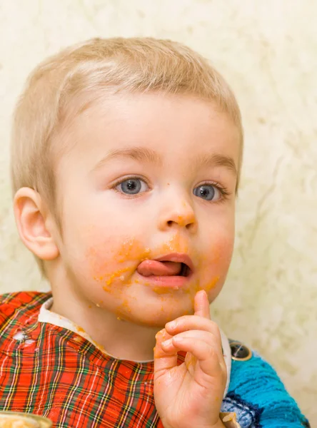 Süße kleine Junge leckt seine Lippen während einer Mahlzeit — Stockfoto