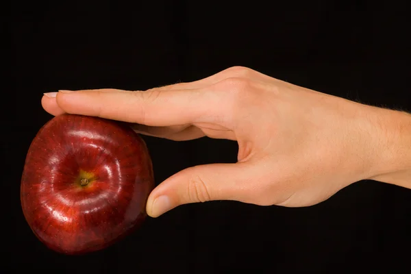 Mannens hand som håller ett äpple över mörk bakgrund — Stockfoto