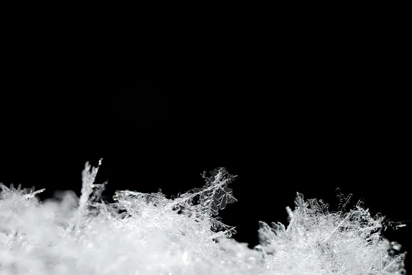 Кристаллы снега на черном — стоковое фото
