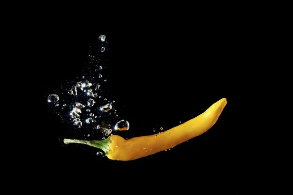 Yellow peppers in water black — Stock Photo, Image