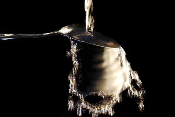 El agua cae brotar en una cuchara — Foto de Stock