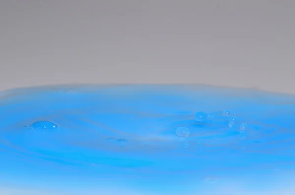 Gouttes dans le liquide bleu — Photo