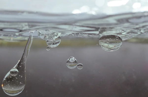 Olie druppels in het transparante water — Stockfoto