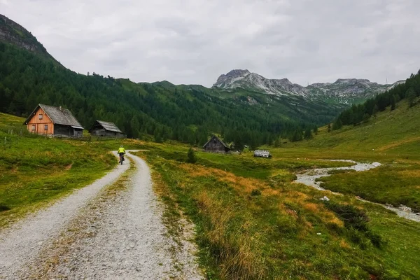 Single Mountainbiker Rijden Door Alpine Hutten Een Bochtige Onverharde Weg — Stockfoto