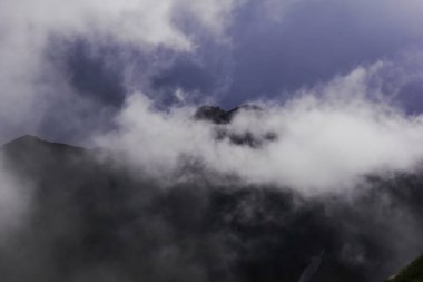 Dağların zirvesinde parlak bulutlar ve sis