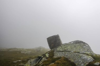Yoğun sis ve güneşte yürürken bir dağın tepesindeki kare kayalar.