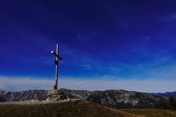 巨大な山脈と青い空を望む山の上の銀の山の十字架 — ストック写真