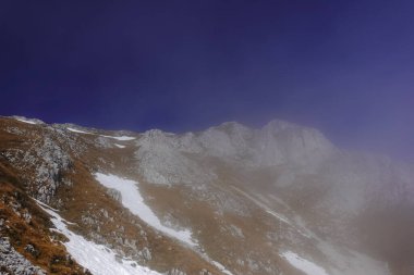 Avustralya 'da kar tarlaları olan bir dağda yürürken mavi gökyüzü olan hafif sis.
