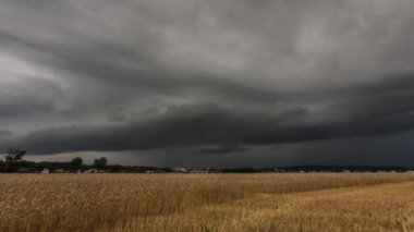 Koyu bulutlu 4k zaman dilimi ve ön planda bir kilise ve mısır tarlası olan bir köyün üzerine yağmur yağması.