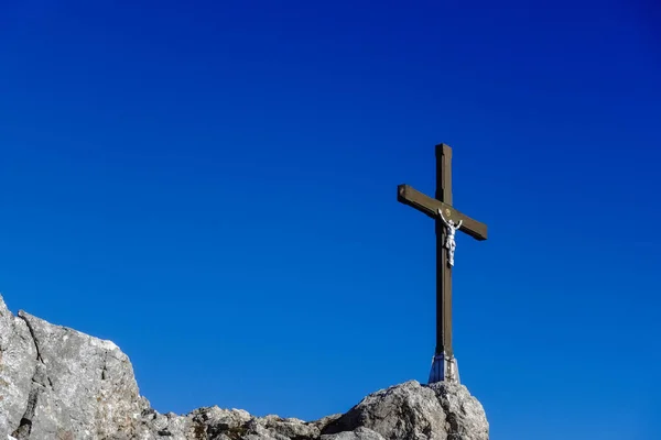頂上の岩の上に白いイエス像と青い空の素晴らしい木製の十字架 — ストック写真