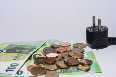 Enerji tüketimi ve elektrik fiyatlarındaki artış. Elektrik prizi detay görünümlü avro faturaları ve sikkeler.