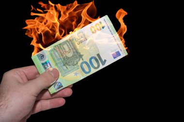 Yanan bir avro banknotunu elinde tutan dünya enflasyonu siyah arkaplanlı