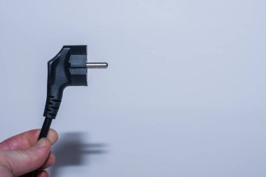 Bir elde tutulan fiş gri arkaplanlı elektrik tasarrufu sağlar