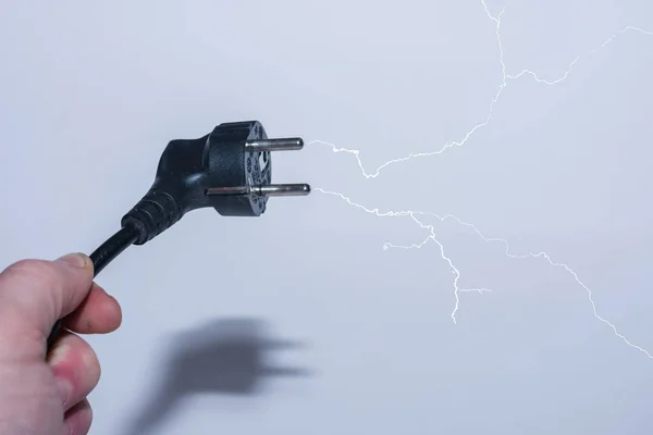 Stecker Schräg Einer Hand Spart Strom Und Ein Verzweigter Blitz lizenzfreie Stockbilder