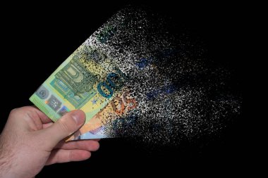 three euro bank notes held in one hand decomposes and dissolves due to inflation with black background clipart