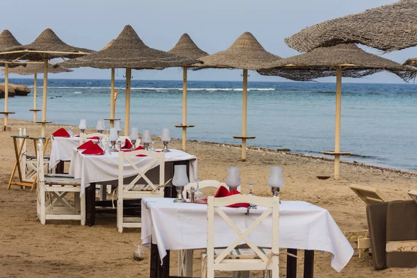 节庆期间 在靠近大海的海滩遮阳伞之间铺了桌子 呈埃及形 — 图库照片
