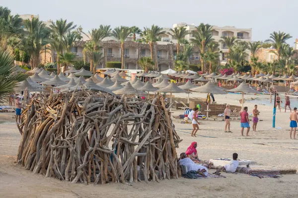 在海上的许多海滩遮阳伞附近用浮木建造的创造性小屋 — 图库照片
