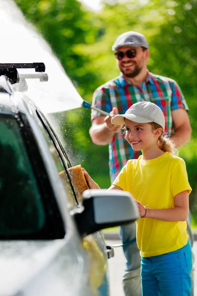 Lavado de coches - niña ayudando a papá a lavar el coche . — Foto de Stock