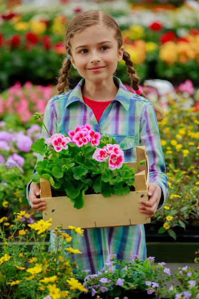 Härlig flicka som håller blommor i trädgården centrum. — Stockfoto