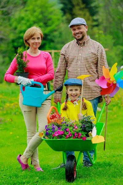 Jardinage - famille heureuse avec brouette travaillant dans le jardin — Photo