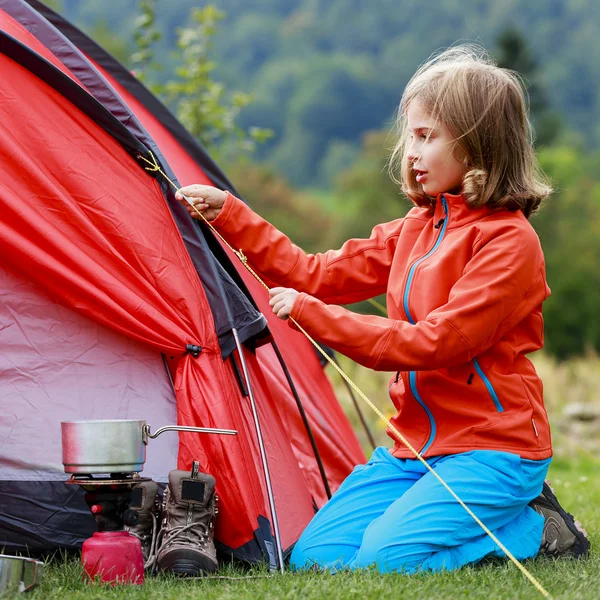 Camper sous la tente - une jeune fille installe une tente sur le camping — Photo