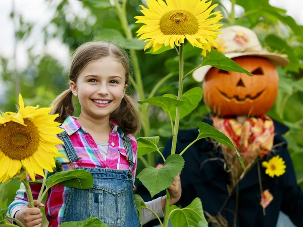 Scarecrow and happy girl in the garden — Stock Photo, Image