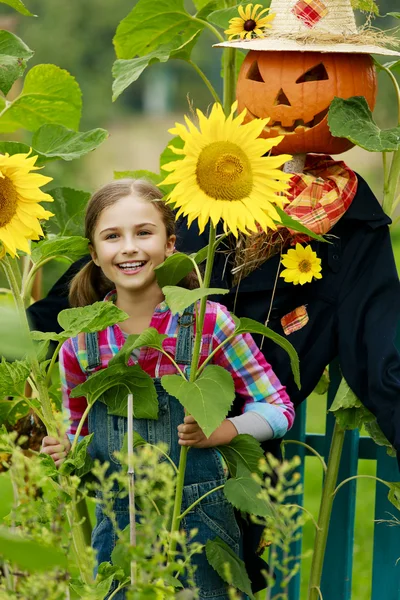 Scarecrow en blij meisje in de tuin — Stockfoto