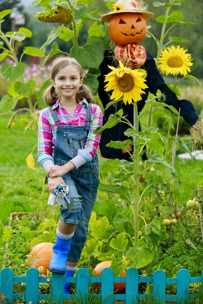 Scarecrow en blij meisje in de tuin — Stockfoto