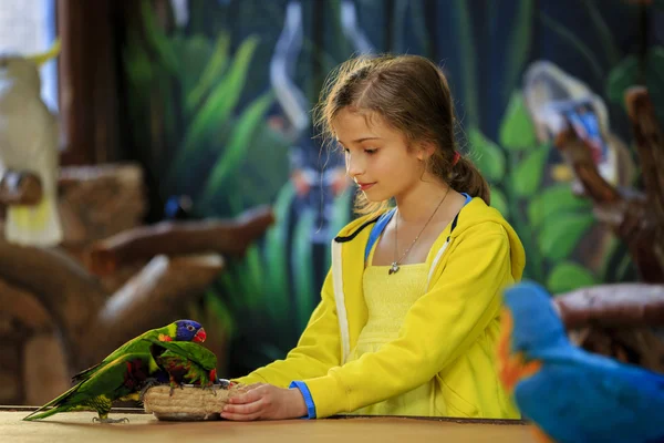 Kirándulás az állatkertben - lány eszik a papagájok az állatkertben — Stock Fotó