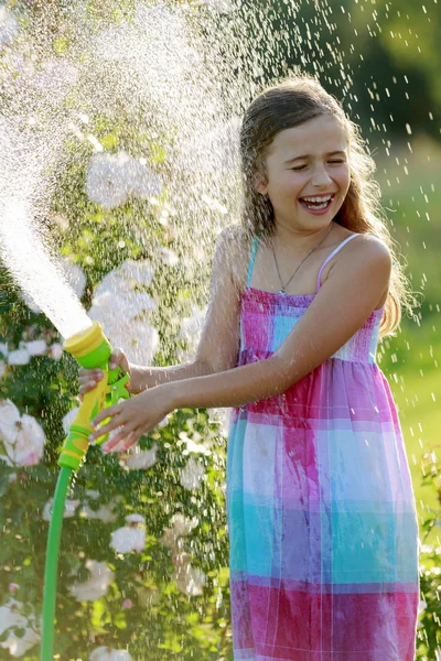 Diversão do verão, flores molhando da menina — Fotografia de Stock