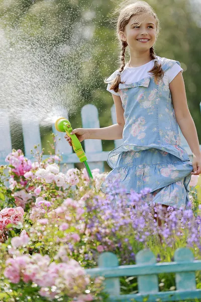 Летнее веселье, девушка поливает цветы — стоковое фото