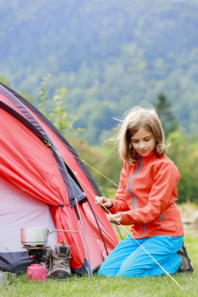 Лагерь в палатке - молодая девушка устанавливает палатку на кемпинг — стоковое фото