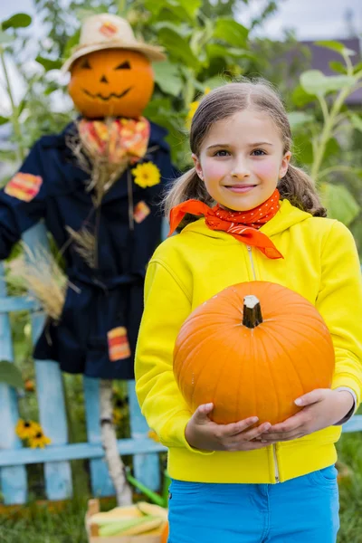 Scarecrow en blij meisje in de tuin - herfst oogsten — Stockfoto