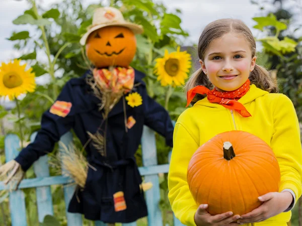 Fågelskrämman och glad tjej i trädgården - hösten skördar — Stockfoto