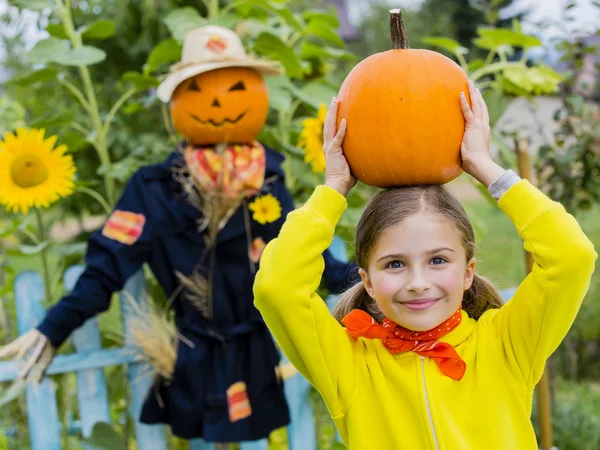 Scarecrow en blij meisje in de tuin - herfst oogsten — Stockfoto