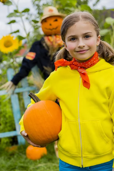 Σκιάχτρο και ευτυχισμένος κορίτσι στον κήπο - φθινόπωρο συγκομιδές — Φωτογραφία Αρχείου