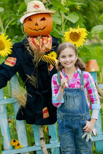 Scarecrow en blij meisje in de tuin — Stockfoto