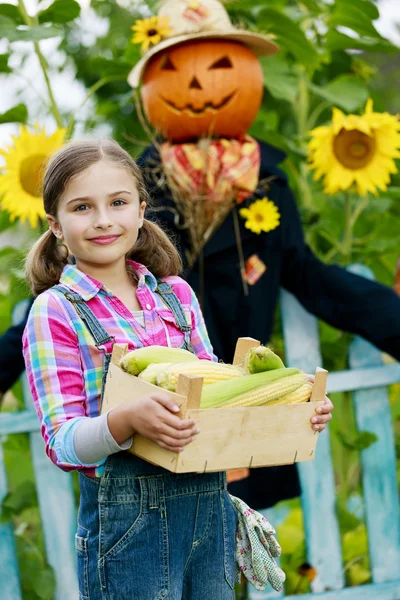 Scarecrow en blij meisje in de tuin - herfst oogsten — Stockfoto