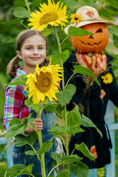 Scarecrow en blij meisje in de tuin — Stockfoto