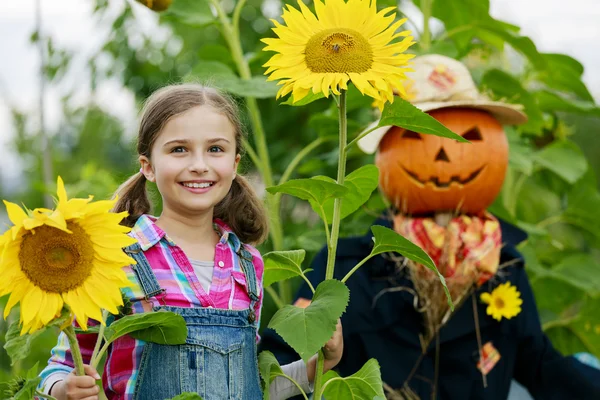 Scarecrow and happy girl  in the garden — Stock Photo, Image