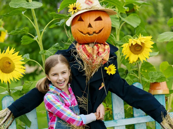 Scarecrow and happy girl  in the garden — Stock Photo, Image