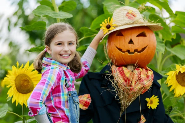 Scarecrow and happy girl  in the garden — Stock Photo, Image