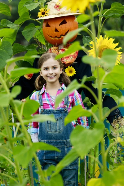 Espantalho e menina feliz no jardim — Fotografia de Stock