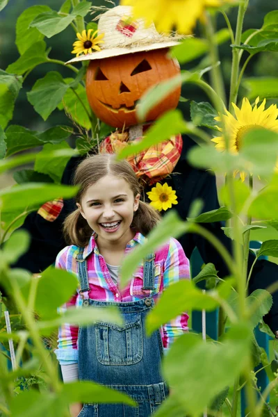 Scarecrow and happy girl  in the garden — Stock Photo, Image