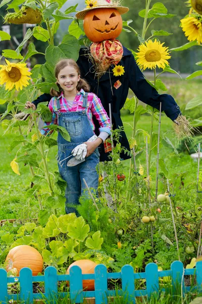 Scarecrow en blij meisje in de tuin — Stockfoto