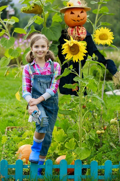 Scarecrow and happy girl  in the garden — Stock Photo, Image