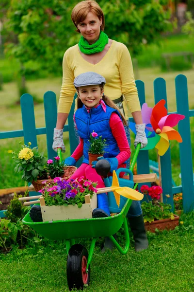 Trädgårdsskötsel - härlig tjej med mor arbetar i blommor trädgård — Stockfoto