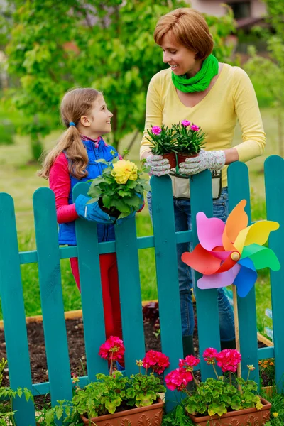 Trädgårdsskötsel - härlig tjej med mor arbetar i blommor trädgård — Stockfoto